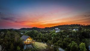 Ein Haus auf einem Hügel mit Sonnenuntergang im Hintergrund in der Unterkunft TN Whiskey Cabin- Lake and Mtn Views- Covered Deck- Game Room- Pool Table- Pets in Sevierville