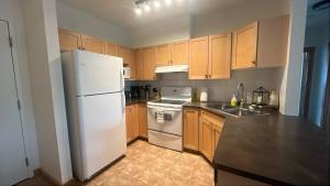a kitchen with wooden cabinets and a white refrigerator at Alpine Vista - Family Fun Pool & Hot Tub in Canmore