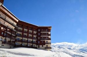 a building in the snow with mountains in the background at Résidence Necou - Studio déco style chalet en bord de pistes MAE-5954 in Les Menuires +11 photos