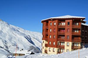 a building in the snow next to a mountain at Résidence Necou - Studio déco style chalet en bord de pistes MAE-5954 in Les Menuires