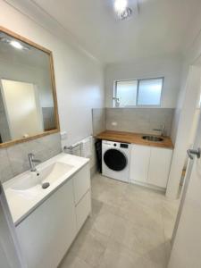 a bathroom with a sink and a washing machine at Sea Salt One Burgess Beach in Forster