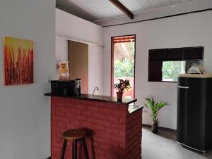a kitchen with a brick fireplace with a counter and stool at Hospedaria Su in Parnamirim