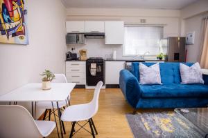 a living room with a blue couch and a kitchen at At twelve Guesthouse in Gaborone