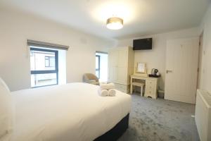 Un dormitorio con una cama blanca grande y un escritorio en The Lodge, en Dunmore