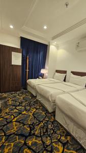 メッカにあるLuluat Al Badaie Hotelのカーペットフロアの客室で、ベッド2台が備わります。