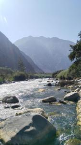 a river with rocks and mountains in the background at La Casa Bella De Lunahuana in Lunahuaná