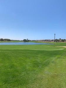 een groot groen veld met water op de achtergrond bij Apartment at Adress Golf in El Alamein