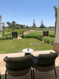 twee stoelen en een tafel op een terras met een park bij Apartment at Adress Golf in El Alamein