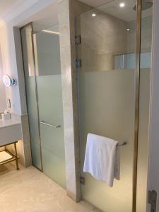 een badkamer met een glazen douche en een witte handdoek bij Apartment at Adress Golf in El Alamein