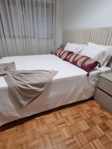 a bed with white sheets and pillows in a bedroom at Apartamento Brisa in Viana do Castelo