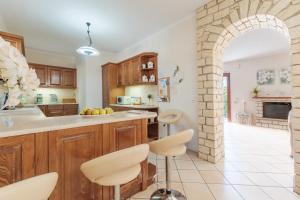 Un arco en una cocina con gabinetes de madera y sillas blancas. en Villa Mylos, en Kassiopi