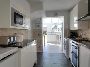 a kitchen with white appliances and a large window at Aafiyat House in Aldershot