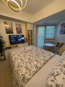 a bedroom with a large bed and a tv at Sweet Retreat Studio Azure North by THE BALI CORNER AT AZURE NORTH, Wavepool, Beach and Mount Arayat view in San Fernando