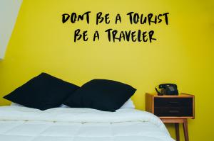 a bedroom with a bed with a yellow wall with a quote at La Joya Hostel in Valparaíso
