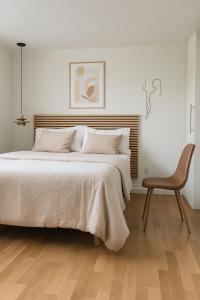a bedroom with a large bed and a chair at Calm Condo in villa area near nature in Vendelsö