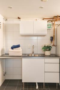 a kitchen with white cabinets and a sink at Calm Condo in villa area near nature in Vendelsö