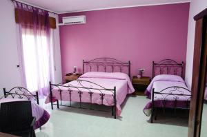 two beds in a room with pink walls at Sicily House in Mazara del Vallo