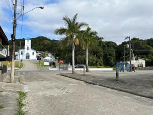 an empty street with a white church and palm trees at Estudio Vila dos Pescadores in São Francisco do Sul