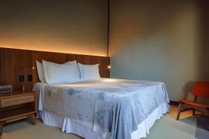 ein Schlafzimmer mit einem großen Bett und einem roten Stuhl in der Unterkunft Villa Toucan in Itacaré