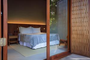 Schlafzimmer mit einem Bett und einer Glastür in der Unterkunft Villa Toucan in Itacaré