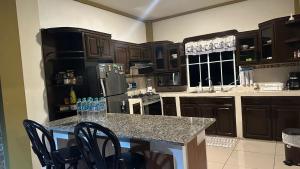a kitchen with black cabinets and a counter with chairs at La Casa de Sonya in Concepción de Ataco