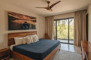 a bedroom with a bed and a ceiling fan at Beachfront 3BR Condo with Private Rooftop and lounge pool, Tankah Bay in Tulum