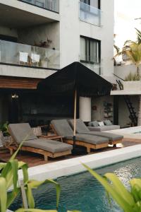 a pool with lounge chairs and an umbrella next to a building at Beachfront 3BR Condo with Private Rooftop and lounge pool, Tankah Bay in Tulum +30 photos