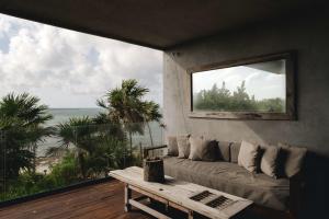 a living room with a couch and a large window at Beachfront 3BR Condo with Private Rooftop and lounge pool, Tankah Bay in Tulum