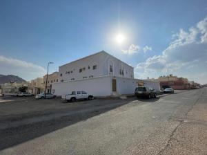 a white building with cars parked in a parking lot at وحدات طيبة in Medina