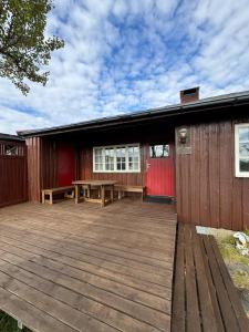 a building with a wooden deck in front of it at Cabin in Silisjávri in Skillemo