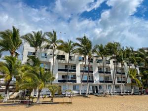 a hotel on the beach with palm trees at Vacacional Luna Mar in Rincon de Guayabitos