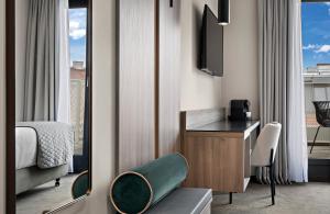 Una habitación de hotel con una cama, un escritorio y un televisor. en Leonardo Hotel Vienna City West, en Viena