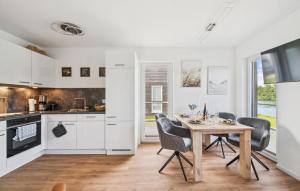 eine Küche mit weißen Schränken und einem Holztisch und Stühlen in der Unterkunft Thor in Tossenserdeich