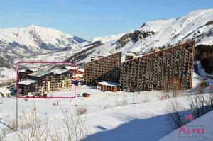 a building in the snow with mountains in the background at Résidence Villaret - 2 Pièces pour 4 Personnes MAE-4101 in Les Menuires