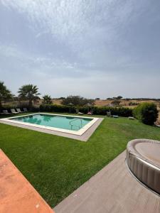 a swimming pool in the middle of a field of grass at Herdade Monte Gordo in Ourique