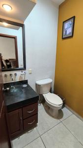 Un baño con inodoro, lavabo y espejo. en Exclusive Luxury condo – Comfort & Style, en Nuevo Nayarit 13 fotos más