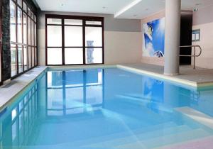 a large swimming pool with blue water in a building at Résidence Le Panoramic - Appartement lumineux · Départ et retour skis aux pieds · Piscine · Parking inclus · Spa MAE-0351 in Magland