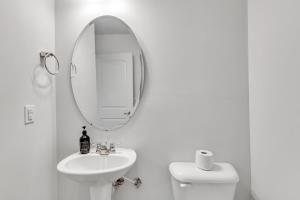 ein weißes Badezimmer mit Waschbecken und Spiegel in der Unterkunft Upscale King 3BR Townhouse Mins to Cary & NC State in Raleigh