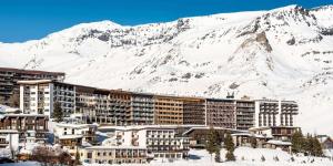 un complexe dans la neige avec une montagne en arrière-plan dans l'établissement Résidence Ducs De Savoie - Appartement 3, proche des pistes,commerce, vue lac MAE-3644, à Tignes