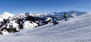 two people skiing down a snow covered mountain at Résidence Le Schuss 1 - Appartement au pied des pistes avec terrasse vue Mont-Charvin MAE-3434 in Notre-Dame-de-Bellecombe