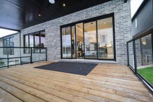 ナイアガラ・フォールズにあるModern 6 Bedroom Masterpiece in Niagara Fallsのガラス窓とレンガ造りの建物のある大きなパティオ