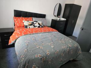 a bedroom with a bed with an orange comforter and pillows at Lovely 3 Bed Ground Floor Apartment Near QE Hospital Harborne Birmingham New in Birmingham