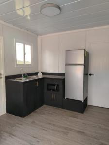 a kitchen with black cabinets and a refrigerator at EcOsaLodge in Puerto Jiménez