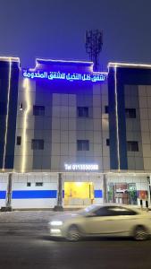 un coche blanco conduciendo delante de un edificio en شقق ظل النخيل للشقق المخدومة, en Hotat bani tamim