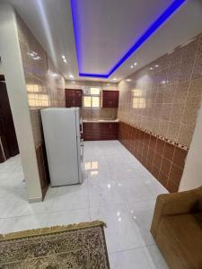 cocina con nevera blanca y techo azul en شقق ظل النخيل للشقق المخدومة, en Hotat bani tamim