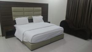 Un dormitorio con una cama grande y una silla. en شقق ظل النخيل للشقق المخدومة, en Hotat bani tamim 2 fotos más