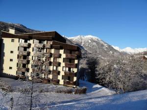 a building in the snow with mountains in the background at Résidence Les Melezes - Studio rénové · Accès pistes par navette · Parking extérieur MAE-0684 in Champcella +8 photos