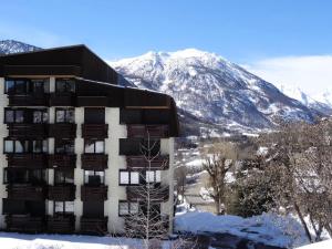 a building in the snow with a mountain in the background at Résidence Les Melezes - Studio rénové & chaleureux · Accès pistes par navettes · Parking extérieur MAE-1104 in Champcella