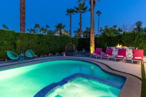 Una piscina con sillas y mesa y palmeras. en Fiesta in the Sun by ACME House Company, en Palm Springs