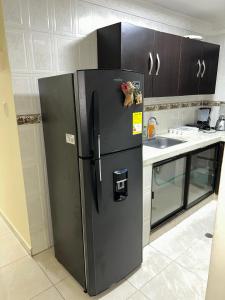 a black refrigerator in a kitchen next to a sink at Hermoso apto piso 2 barrio san jose in Barranquilla
